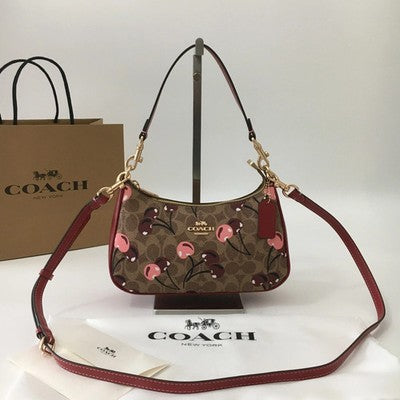 Coach Teri shoulder bag in tan signature coated canvas with cherry print, zip-top closure, detachable handle, and crossbody strap
