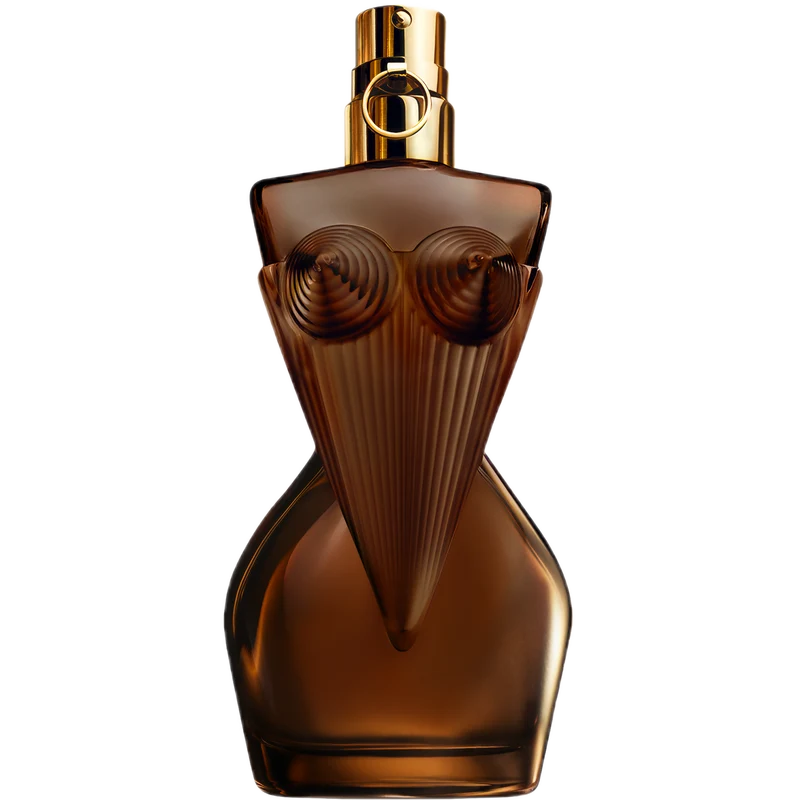 A sculptural amber-brown perfume bottle shaped like a stylized female torso with ribbed details, a gold spray top, and a circular logo medallion on the neck, isolated on a black background.