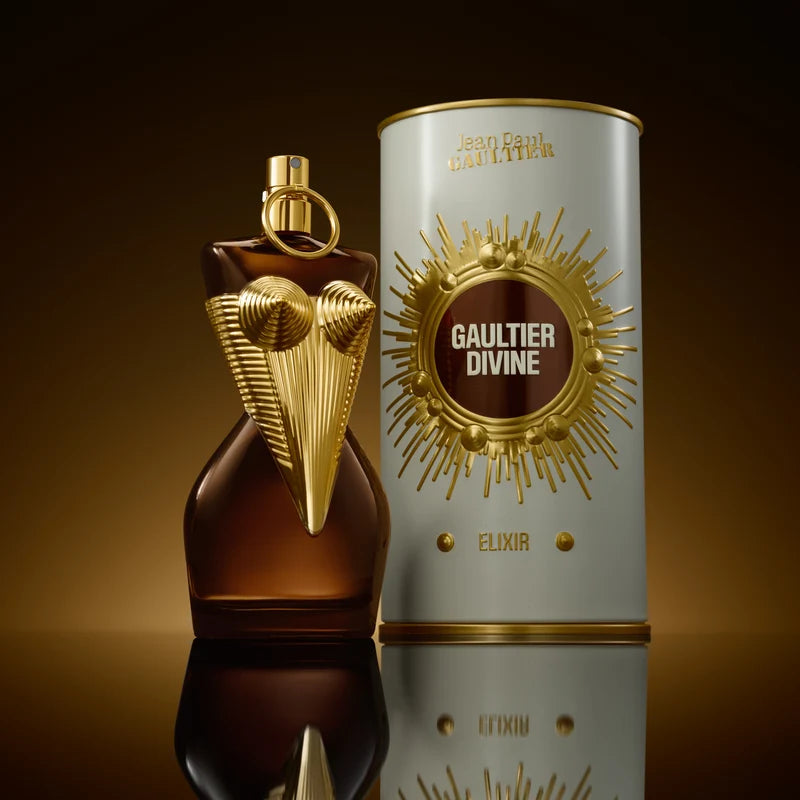 Perfume bottle and packaging of Gaultier Divine Elixir on a reflective surface with a dark background